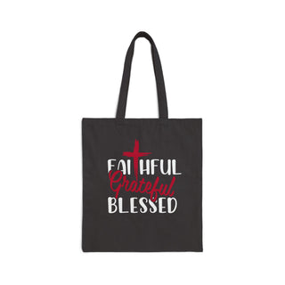 A black canvas tote bag with two shoulder straps, featuring a printed graphic on the front. The graphic displays a red cross above the words 'FAITHFUL', 'Grateful', and 'BLESSED' in white and red lettering, set against a plain white background.