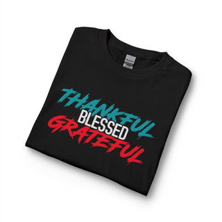 A folded black Gildan t-shirt with a graphic print reading 'THANKFUL BLESSED GRATEFUL' in teal, white, and red stylized fonts, displayed on a clean white background.