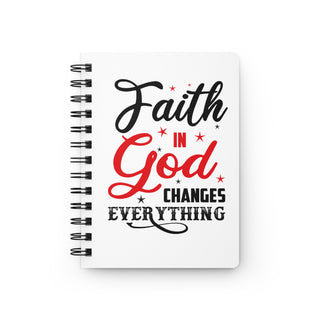 A white spiral-bound notebook with a black wire binding and a bold typographic cover design reading 'Faith in God Changes Everything' in black and red lettering with small red stars, shown on a clean white background.