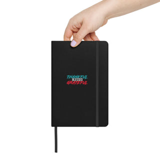 Black Notebook with Hand Holding it that says Thankful Blessed Grateful