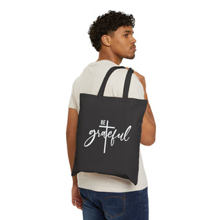 Man carrying a black tote bag with a Be Grateful Design on a White background